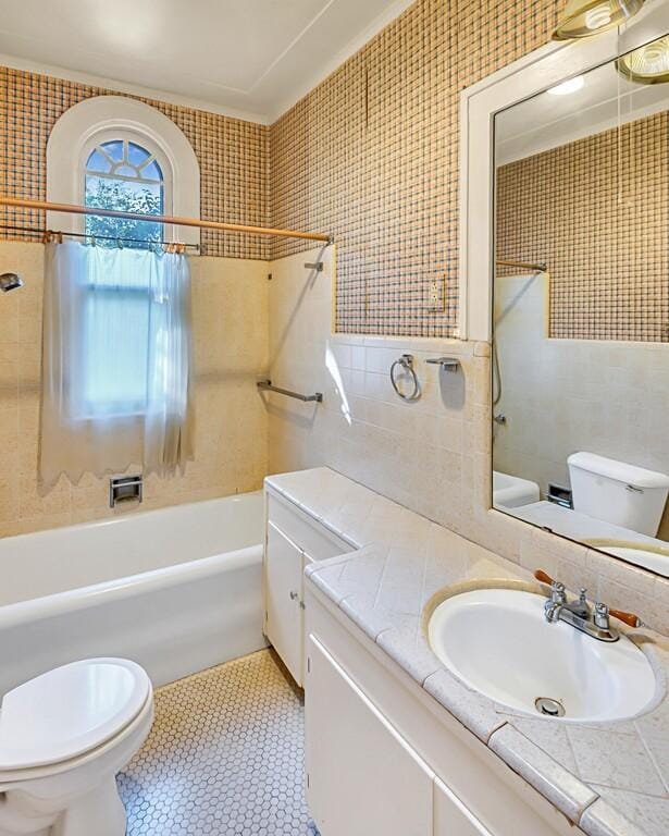 full bathroom featuring vanity, toilet, tile walls, and tiled shower / bath