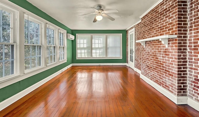 unfurnished sunroom featuring an AC wall unit, a wealth of natural light, and ceiling fan