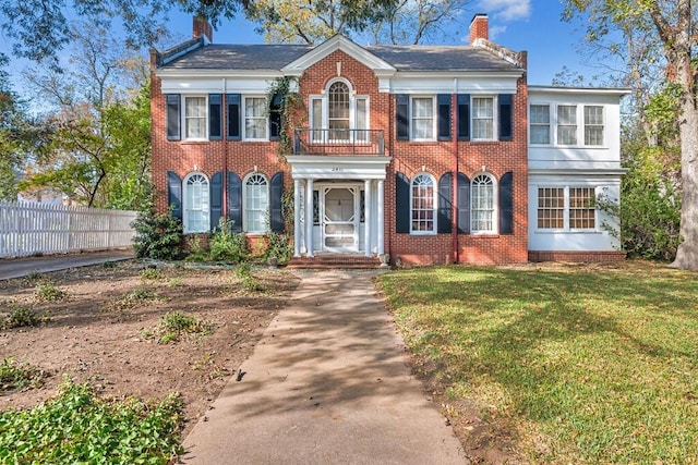 colonial house with a balcony and a front lawn