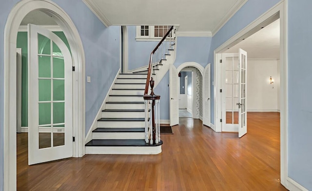 stairs with hardwood / wood-style floors, french doors, and ornamental molding