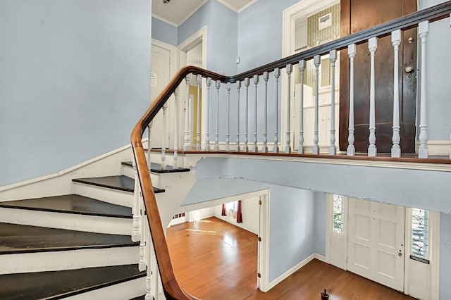 stairs featuring wood-type flooring and ornamental molding