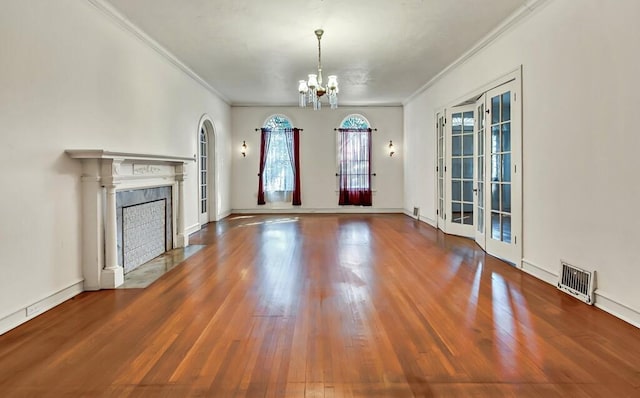 unfurnished living room with a chandelier, french doors, hardwood / wood-style flooring, and crown molding