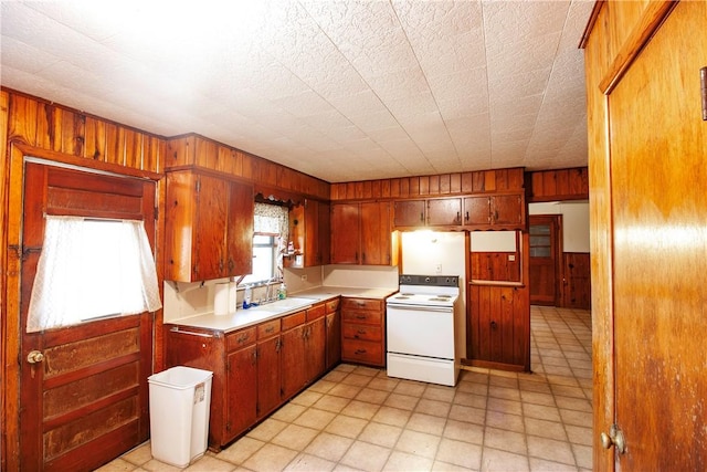 kitchen with wooden walls, sink, a textured ceiling, and white electric stove