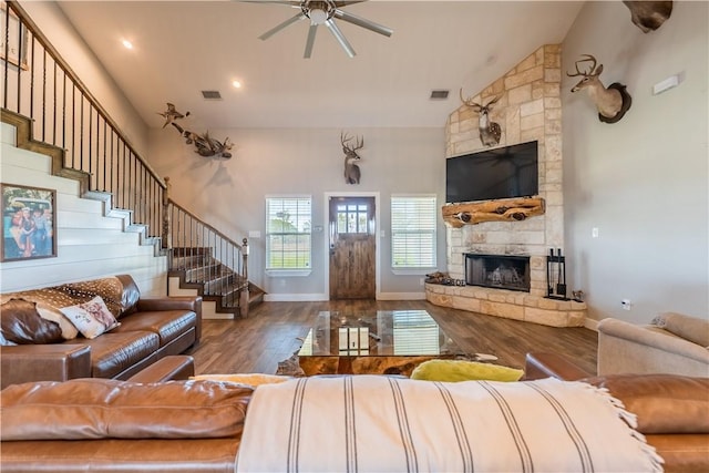 living room with a stone fireplace, ceiling fan, high vaulted ceiling, and hardwood / wood-style flooring