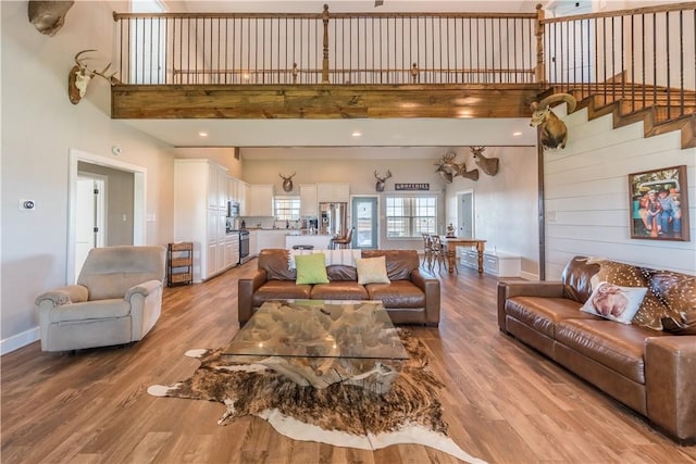 living room with light hardwood / wood-style flooring, a towering ceiling, and sink