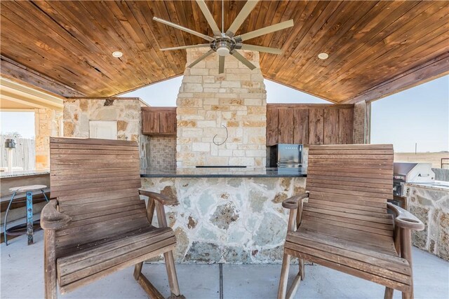 view of patio / terrace featuring a grill, ceiling fan, a bar, and exterior kitchen