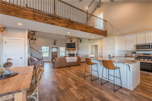 kitchen with white cabinets, stainless steel appliances, high vaulted ceiling, and a kitchen island with sink