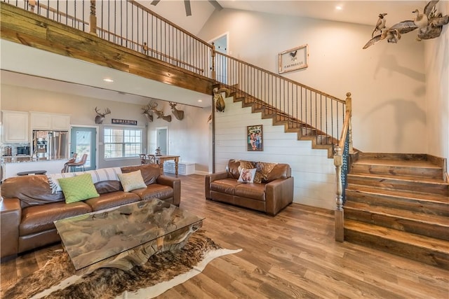 living room with ceiling fan, high vaulted ceiling, and light wood-type flooring