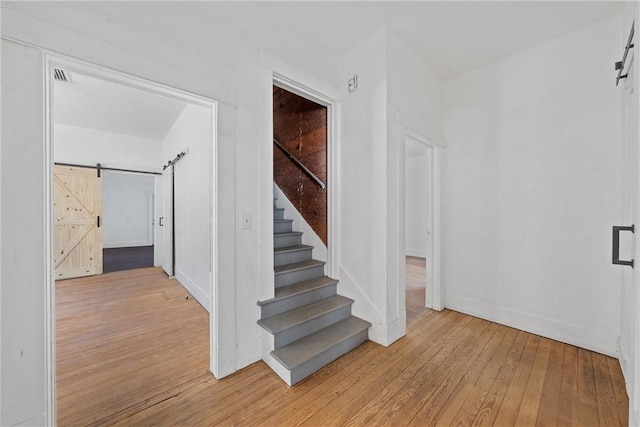 stairway with a barn door and hardwood / wood-style flooring