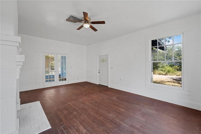 unfurnished living room with french doors, a brick fireplace, ceiling fan, and dark wood-type flooring