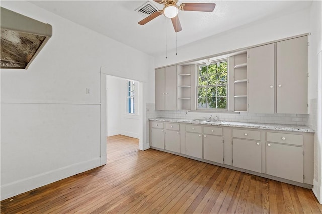 kitchen with gray cabinetry, ceiling fan, sink, decorative backsplash, and light wood-type flooring