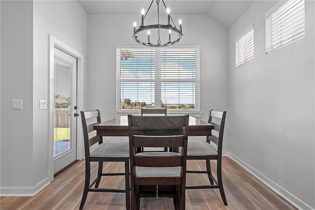 dining space with baseboards, a notable chandelier, and wood finished floors