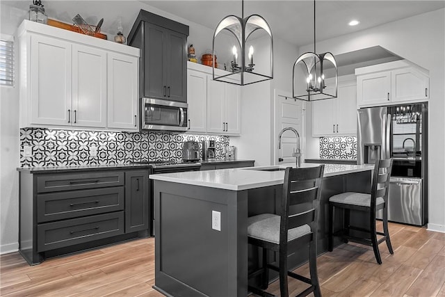 kitchen featuring appliances with stainless steel finishes, light wood-type flooring, a kitchen breakfast bar, and an island with sink