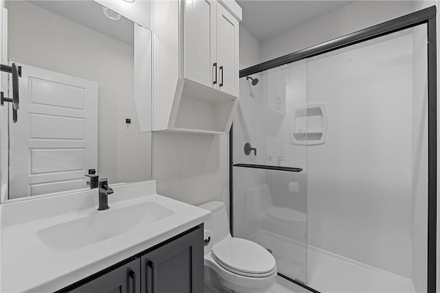 bathroom featuring vanity, a shower stall, and toilet