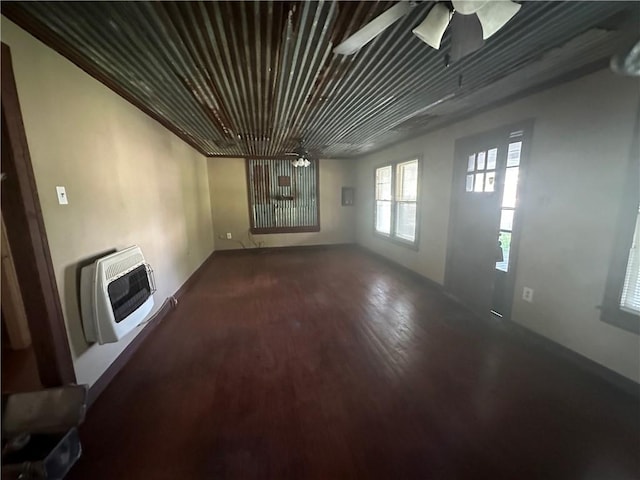 unfurnished living room with dark hardwood / wood-style floors, ceiling fan, and heating unit