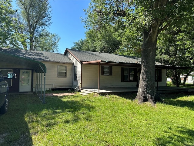 back of house with a carport and a lawn