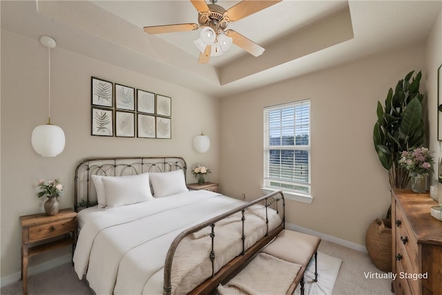 bedroom with carpet flooring, a raised ceiling, and ceiling fan