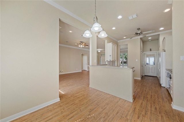 kitchen with kitchen peninsula, white fridge, light hardwood / wood-style flooring, and hanging light fixtures