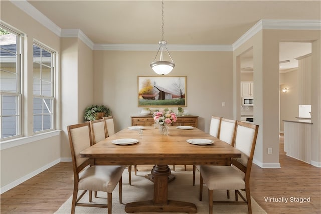 dining area with ornamental molding and light hardwood / wood-style flooring