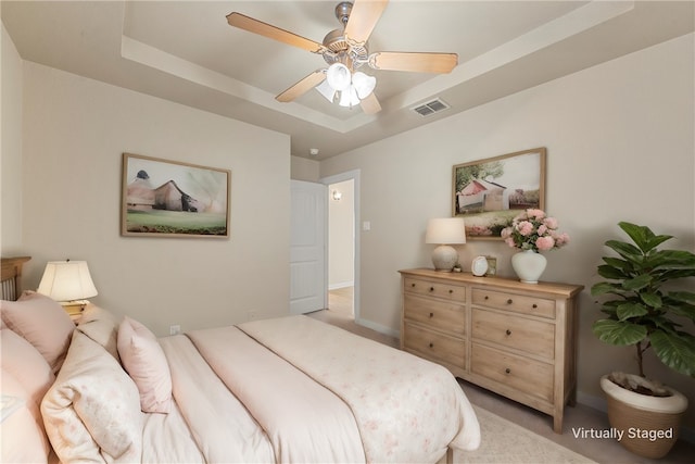 carpeted bedroom featuring ceiling fan and a tray ceiling