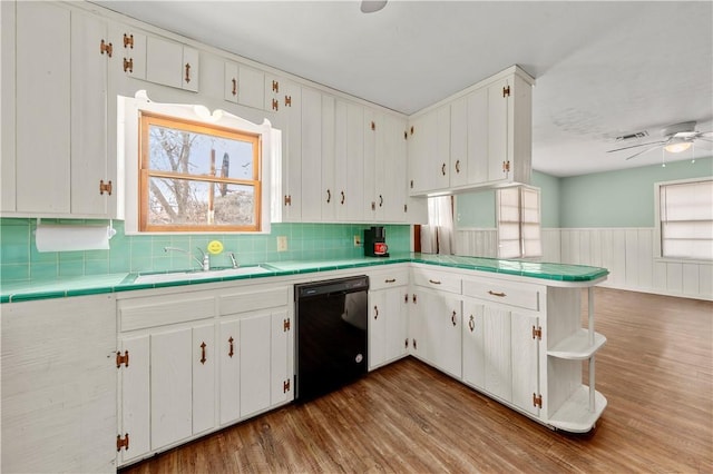 kitchen featuring a healthy amount of sunlight, sink, black dishwasher, and white cabinetry