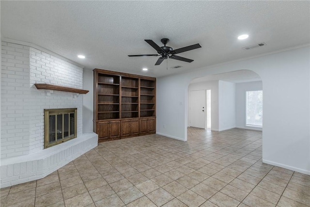 unfurnished living room featuring ceiling fan, a fireplace, light tile patterned flooring, and a textured ceiling