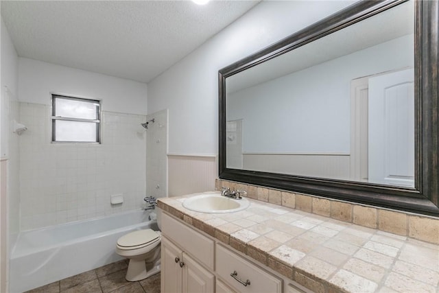 full bathroom featuring tiled shower / bath combo, tile patterned floors, a textured ceiling, toilet, and vanity