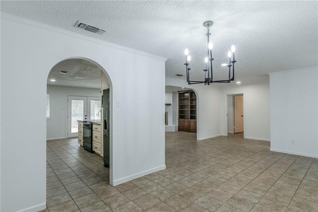 tiled spare room featuring an inviting chandelier, crown molding, a textured ceiling, and french doors