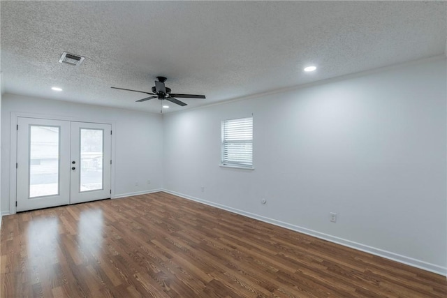 spare room featuring a textured ceiling, ceiling fan, dark wood-type flooring, and french doors