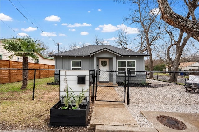 view of front of home with a fenced front yard, a gate, a front lawn, and a shingled roof