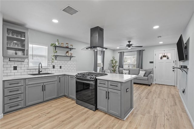 kitchen featuring visible vents, stainless steel range with gas cooktop, island exhaust hood, and gray cabinetry