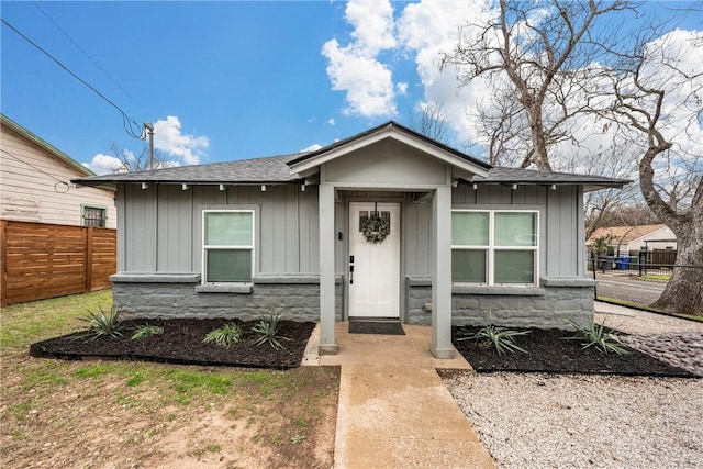 bungalow-style home with fence, board and batten siding, and roof with shingles