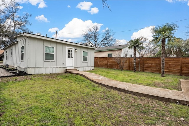 rear view of property with entry steps, a lawn, and a fenced backyard