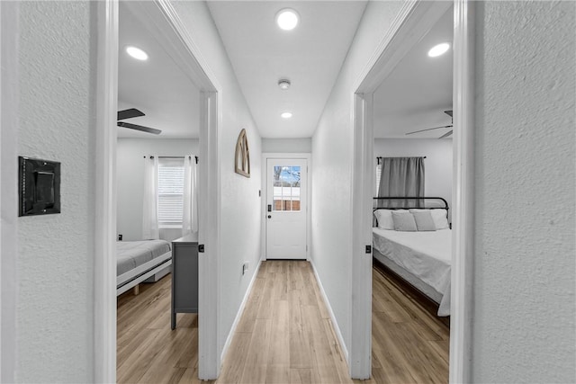 corridor with recessed lighting, light wood-type flooring, and baseboards