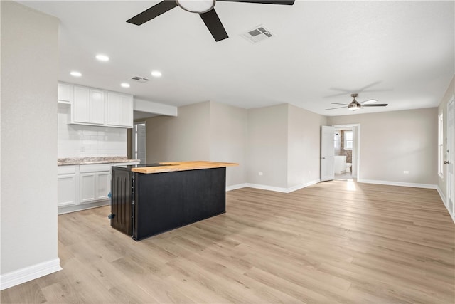 kitchen with wooden counters, backsplash, white cabinets, light hardwood / wood-style floors, and a kitchen island