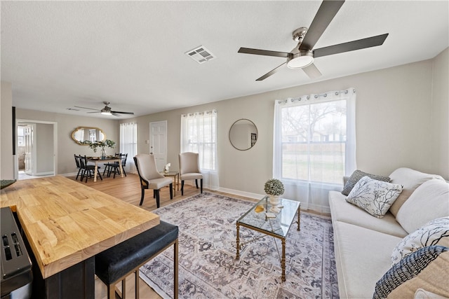 living room featuring ceiling fan, hardwood / wood-style flooring, and a textured ceiling