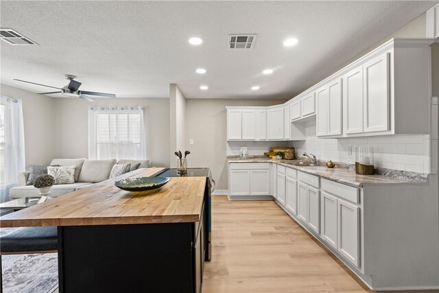 kitchen featuring white cabinets, sink, light hardwood / wood-style flooring, decorative backsplash, and stainless steel electric range oven