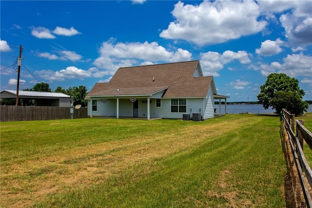 back of property featuring a lawn, central air condition unit, and a water view