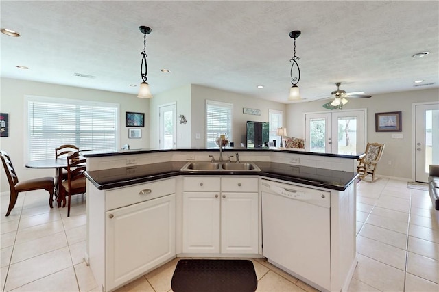 kitchen featuring white dishwasher, a kitchen island with sink, and a wealth of natural light