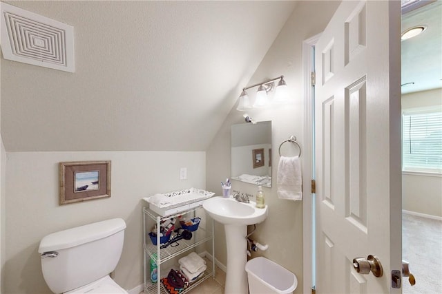 bathroom featuring toilet, sink, and vaulted ceiling