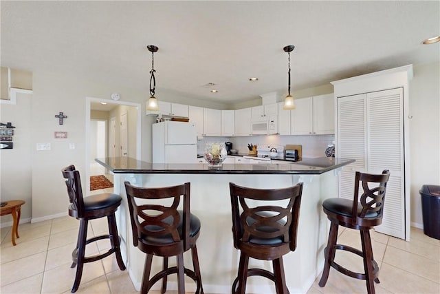 kitchen with a kitchen bar, white cabinetry, hanging light fixtures, and white appliances