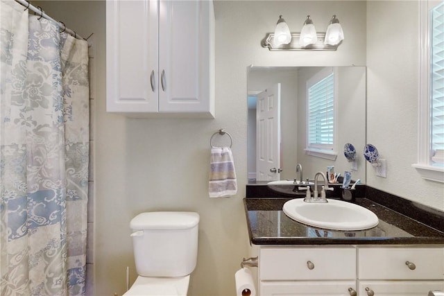 bathroom featuring curtained shower, vanity, and toilet