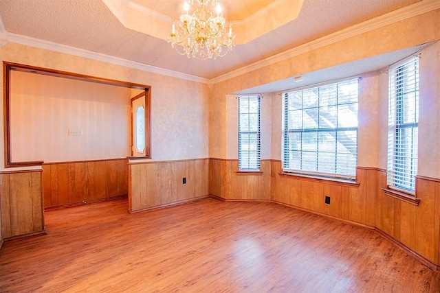 unfurnished room with a chandelier, a textured ceiling, and light wood-type flooring