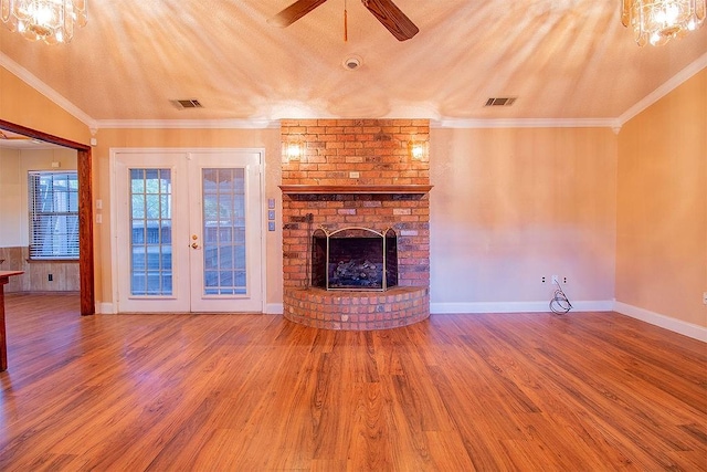 unfurnished living room featuring a brick fireplace, crown molding, french doors, and hardwood / wood-style flooring