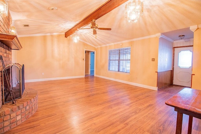 unfurnished living room with ornamental molding, ceiling fan, lofted ceiling with beams, a fireplace, and hardwood / wood-style floors