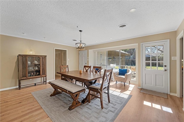 dining room featuring a chandelier, a textured ceiling, and light wood-type flooring