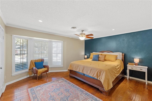 bedroom featuring multiple windows, ceiling fan, hardwood / wood-style floors, and a textured ceiling