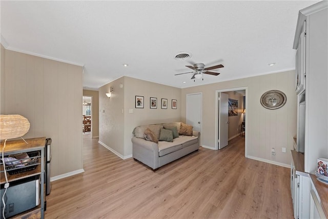 living room with ceiling fan, crown molding, and light hardwood / wood-style floors