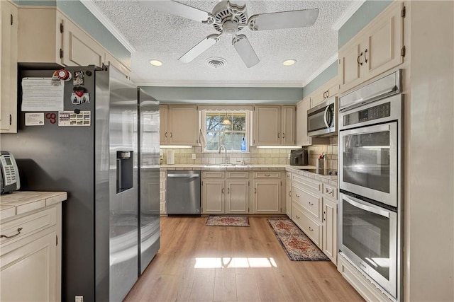 kitchen featuring tasteful backsplash, sink, stainless steel appliances, and ornamental molding