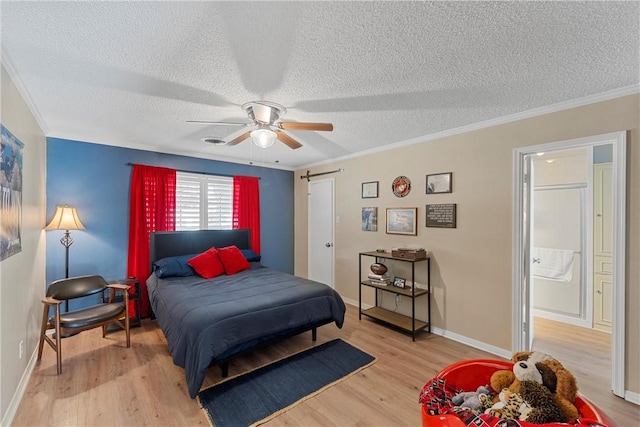 bedroom with ceiling fan, a barn door, ornamental molding, a textured ceiling, and light hardwood / wood-style floors